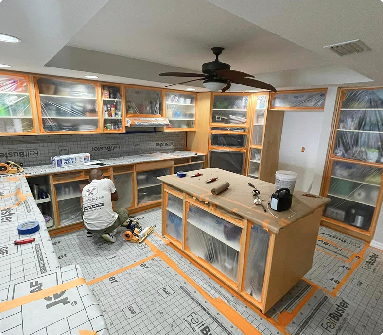 Cabinet painting preparation area with masked cabinets, tools, and protective coverings, showcasing a detail-driven process for high-quality finishes.