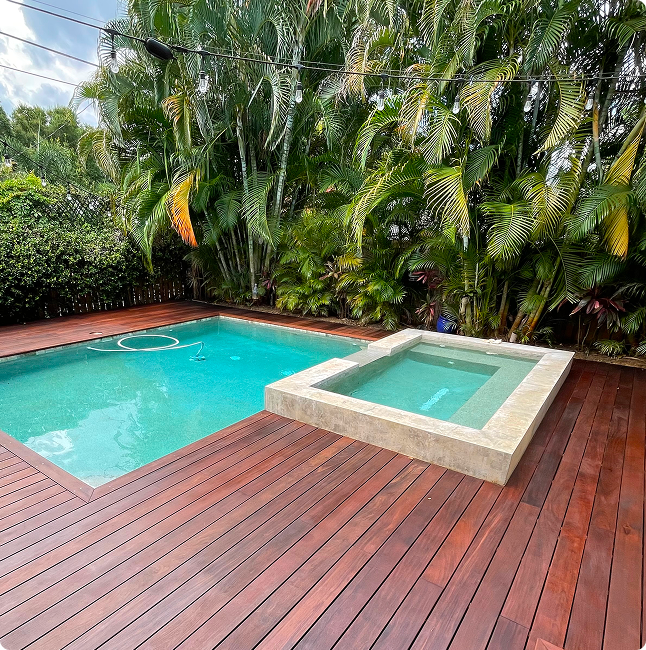 Pool and spa area with wooden decking surrounded by lush tropical plants, showcasing a tranquil outdoor space ideal for Florida's climate.