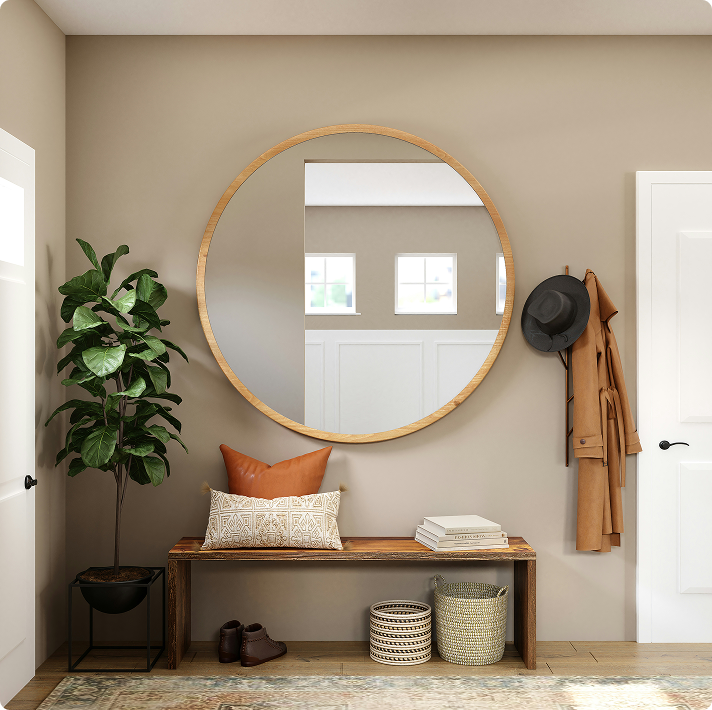 Modern entryway featuring a round mirror, a wooden bench with decorative pillows, a potted plant, and a coat hanging on the wall, highlighting a clean and inviting space for commercial property aesthetics.