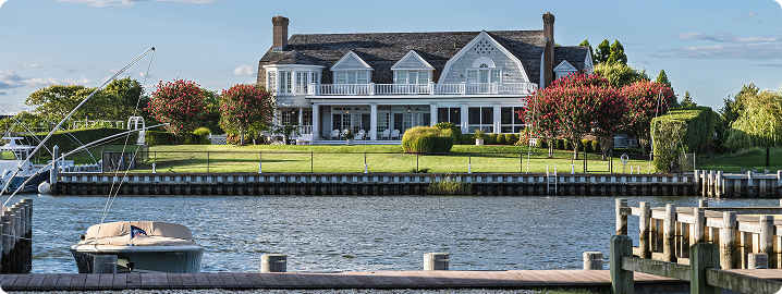 Coastal home with landscaped yard and colorful trees, overlooking waterway, emphasizing the importance of durable paint for Florida's climate.
