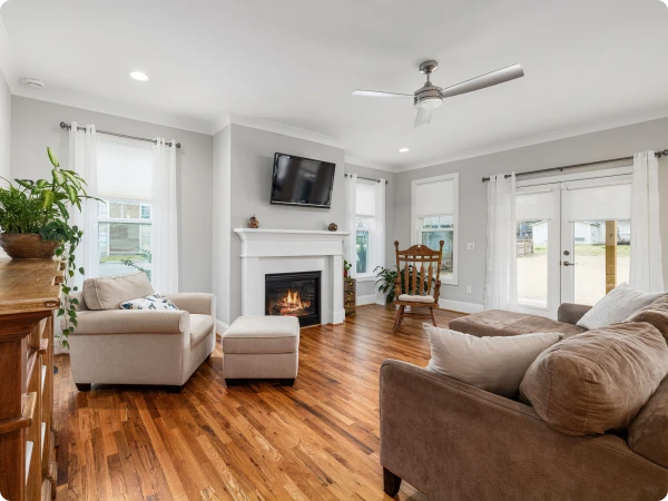 Living room with a white fireplace, light gray walls and hardwood floors