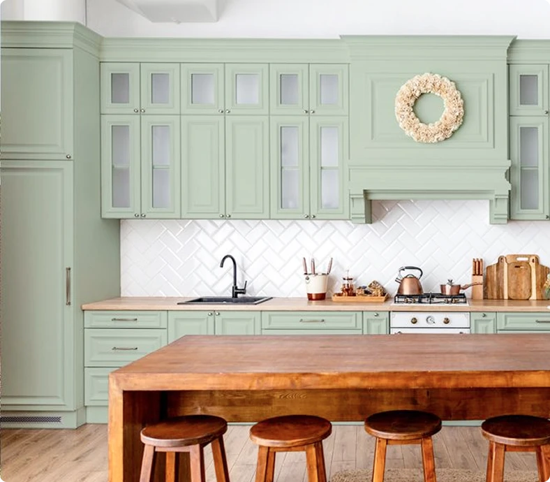 Sage green kitchen cabinets with a wood-topped island and stools