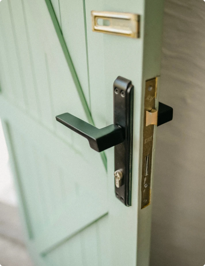 Mint green interior door with a black lever handle and deadbolt