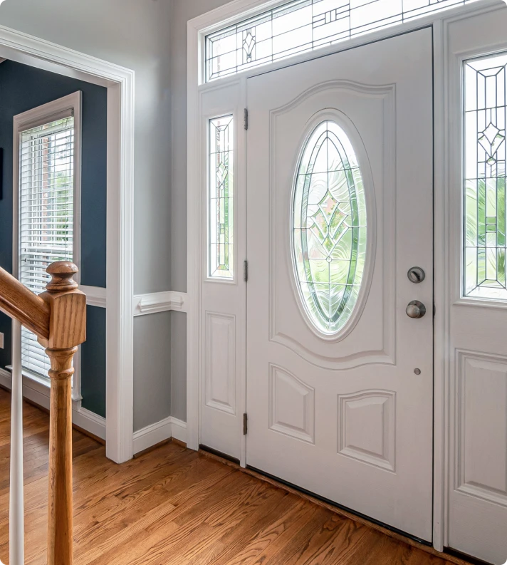White front door with an oval glass insert and sidelights, seen from the entry